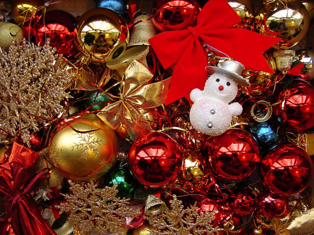 An assortment of colourful Christmas decorations including a snowman, baubles and a bow.