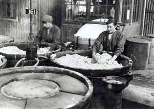 Two munitions workers mixing the cordite in large nitrating pans.
