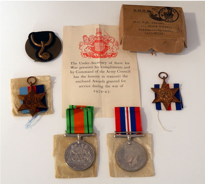Four medals and a cardboard box with a letter.