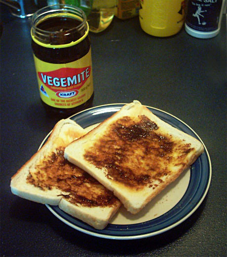 A jar of vegemite with some vegemite on toast.