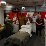A group of living history reenactors and one of our museum team. Stand in set up with objects and photos from WW1.