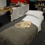 A bed with some newspapers on in The Devil's Porridge Museum's education room.