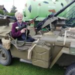 One of our museum team in a military vehicle from the past holding a gun.