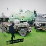 A rainy photo of some vehicles and Sir James outside The Devil's Porridge Museum.