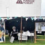 A suffragette stand with two smiling reenactors outside The Devil's Porridge Museum.