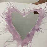 A heart cut out of paper with a border made out of purple ink around it.