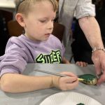 A child painting a stone with dark green.
