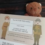 A piece of card with a small toy bear stood behind it. The card has some text and a cartoon munition worker and soldier on it.