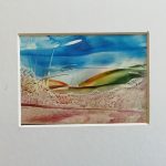 A piece of wax art of a landscape with a bright blue sky and green hills.