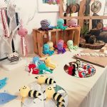 A selection of colourful knitted items made by the Scotia Crafters on display. These creatures include bees, jellyfish, octopi, rainbows and a owl.