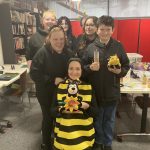 An assortment of people who helped make the bee event happen. They all look happy and one is dressed as a bee.