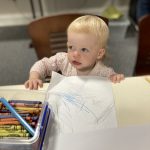 A toddler drawing at The Devil's Porridge Museum's bee event.