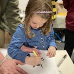 A child drawing a bee related design. The child looks very focused.
