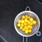 Some yellow tomatoes in a colander.
