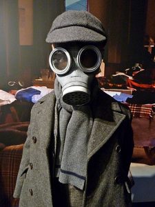 A creepy child wearing a gas mask with a hat on