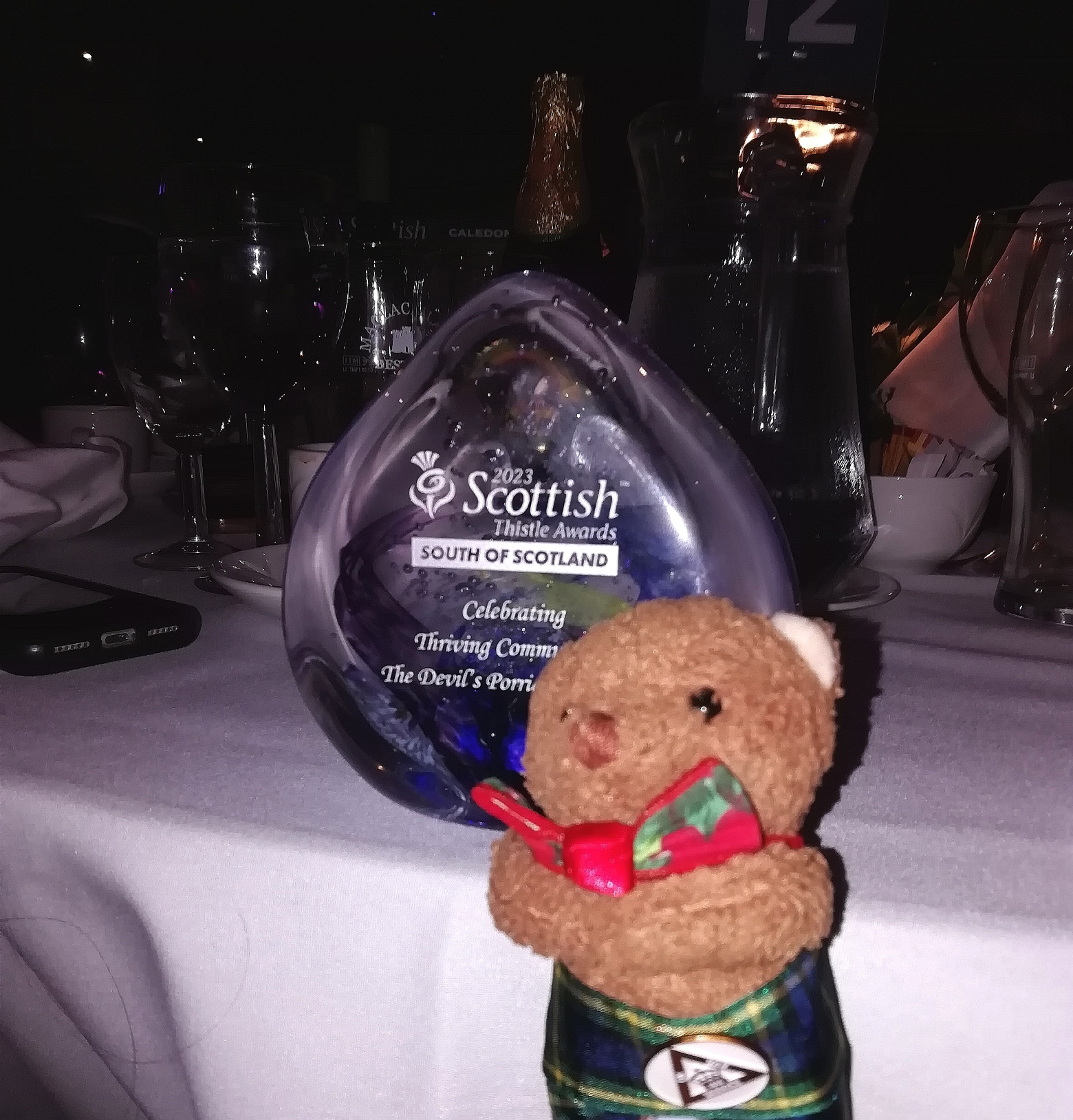 A Thistle Award for 'Celebrating Thriving Communities' with a bear toy stood in front of it.
