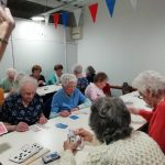 Two rows of tables of members of the Cordite Club playing cards.
