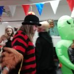 A member of our museum team walks past. She is dressed as Freddy Krueger. A child in an inflatable alien costume and a lady dressed as a witch can be seen in the background.
