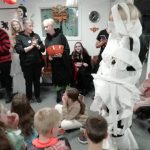 Children sit on the floor around a standing adult wrapped in bandages. Some members of our museum team stood in front of the children discuss the best dressed mummy in this Halloween game.