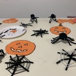 A table containing items that the young people at this workshop has made. This includes paper pumpkins, pipe cleaner spiders and spiders webs.