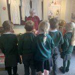 A museum trustee stands before a group of school children in the Gretna Girls bedroom section of The Devil's Porridge Museum