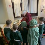 A group of children gather around one of The Devil's Porridge Museum's trustees in the Gretna girls bedroom section of the museum.