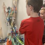 Some children looking at a sculpture made out of recycled materials.