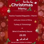 A burgundy Christmas menu for The Devil's Porridge Museum's café. It reads 'Festive Toasted Baguette / Panini with your choice of filling Turkey & Trimmings OR Brie & Cranberry Sauce £6.50. Served from 10:30am to 2pm. Christmas Menu served from 13th November to 10th December 2023.'
