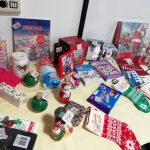 A table full of tombola prizes. This includes shower gel, bubble bath, colouring in, a box of Christmas cards, a festive book, a Christmassy puzzle, Christmas stockings and more.,