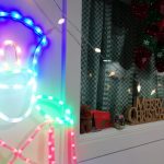 A light up Christmas soldier decoration next to a Merry Christmas sign, a toy bear and some festive string lights.