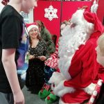 A child stands in front of Santa. The child looks happy.