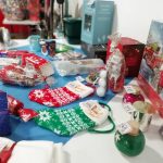 A selection of festive raffle prizes arranged on a table. These include Christmas stockings, a puzzle and bath bombs.