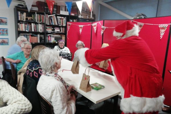 Cordite 4th Dec 2023 23 Santa gives out Christmas gift bags to a table of people.