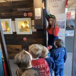 A line of children stand behind The Devil's Porridge Museum's Youth and Community Engagement Officer inside The Devil's Porridge Museum.