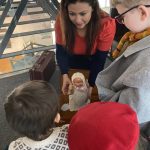 The Devil's Porridge Museum's Youth and Community Engagement Officer shows some children a toy doll.
