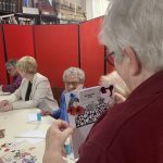 A member of our museum team holding a card with a calendar on.