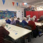 Three rows of tables with people sitting at them. This is The Devil's Porridge Museum's Cordite Club and they are playing cards.