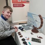The young curator building a Lego planet. He looks happy.