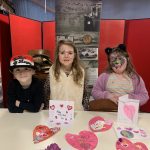 Three young people with the Valentines cards and hearts they made.
