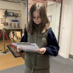 A young person looking at a clipboard inside The Devil's Porridge Museum.