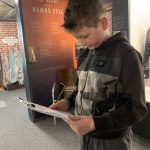 A young person looking at a clipboard in The Devil's Porridge Museum.