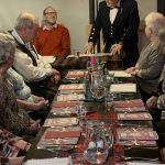 People sitting around a table set for Burns Supper.,