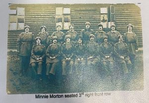 A group of munition workers sat outside, which includes Minnie Morton.