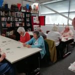 Two tables of cordite club members playing cards.