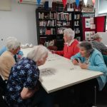 A table of Cordite Club attendees talking and playing cards.