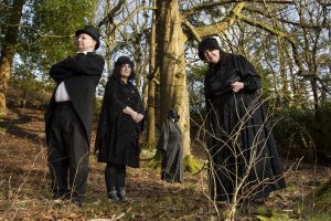 A group of people, called Mostly Ghostly, outside in some woodland.