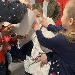 Children dressing an adult up to look like a snowman.