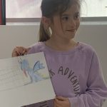 A young person holding the artwork they have created at Mostly Ghostly's event in The Devil's Porridge Museum.