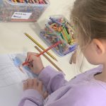 A child drawing with colouring pencils.
