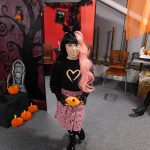 A young person in their Halloween costume holding a pumpkin.